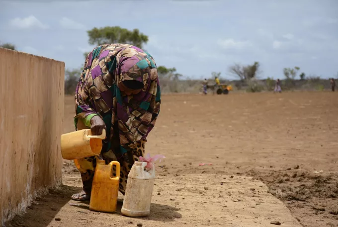 Woman filling bottles with water at a public well. 