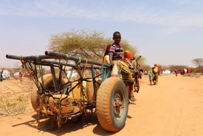 Child sitting on a home-made carriage in desert landscape 